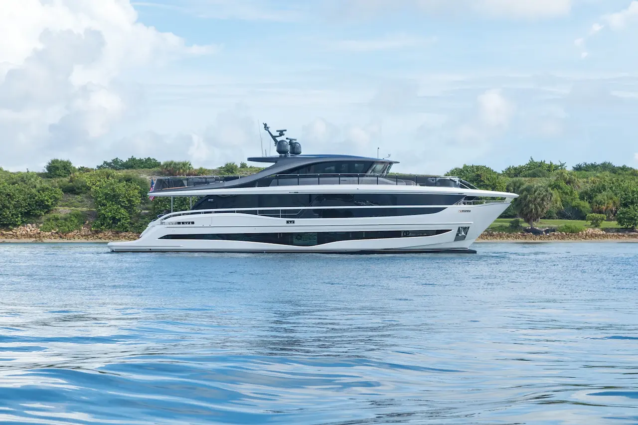 Een luxe Princess Yachts motorjacht vaart langs een groene kustlijn onder een lichte bewolkte hemel.