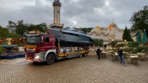 Een vrachtwagen vervoert een jacht van Princess Yachts door een sfeervol plein met Oosterse architectuur.