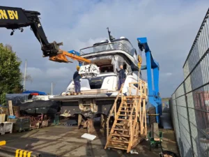 Een Princess Yacht wordt geüpgraded op een werf met behulp van een kraan en werkplatformen.