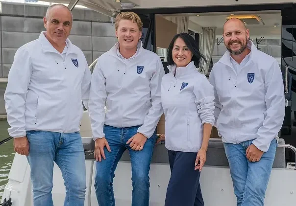 Een team van vier mensen in witte jassen poseert op een jacht van Princess Yachts tijdens een evenement aan het water.