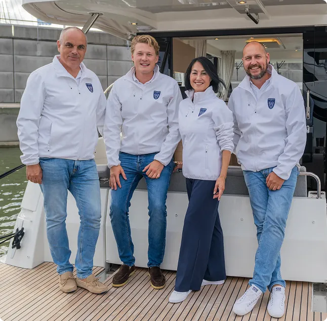 Een team van vier mensen in witte jassen poseert op een jacht van Princess Yachts tijdens een evenement aan het water.