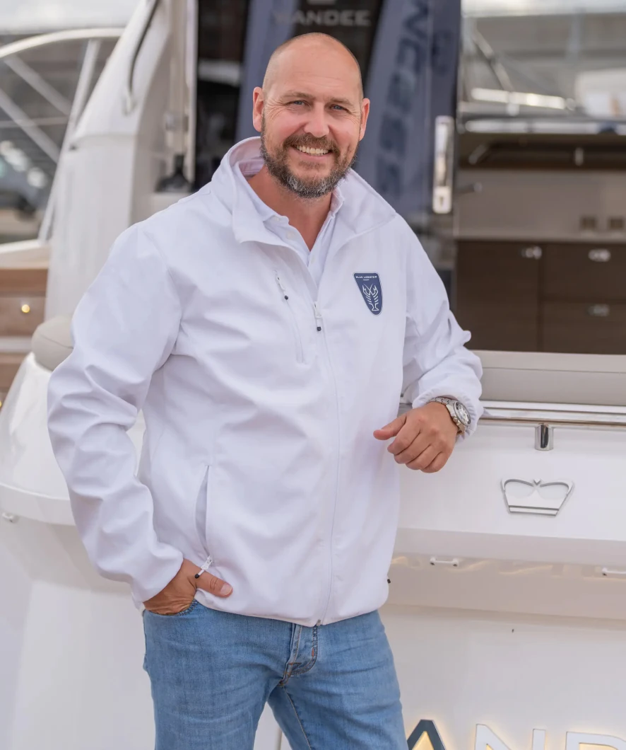 Een man in een witte jas poseert voor een luxe jacht van Princess Yachts tijdens HISWA 2025.