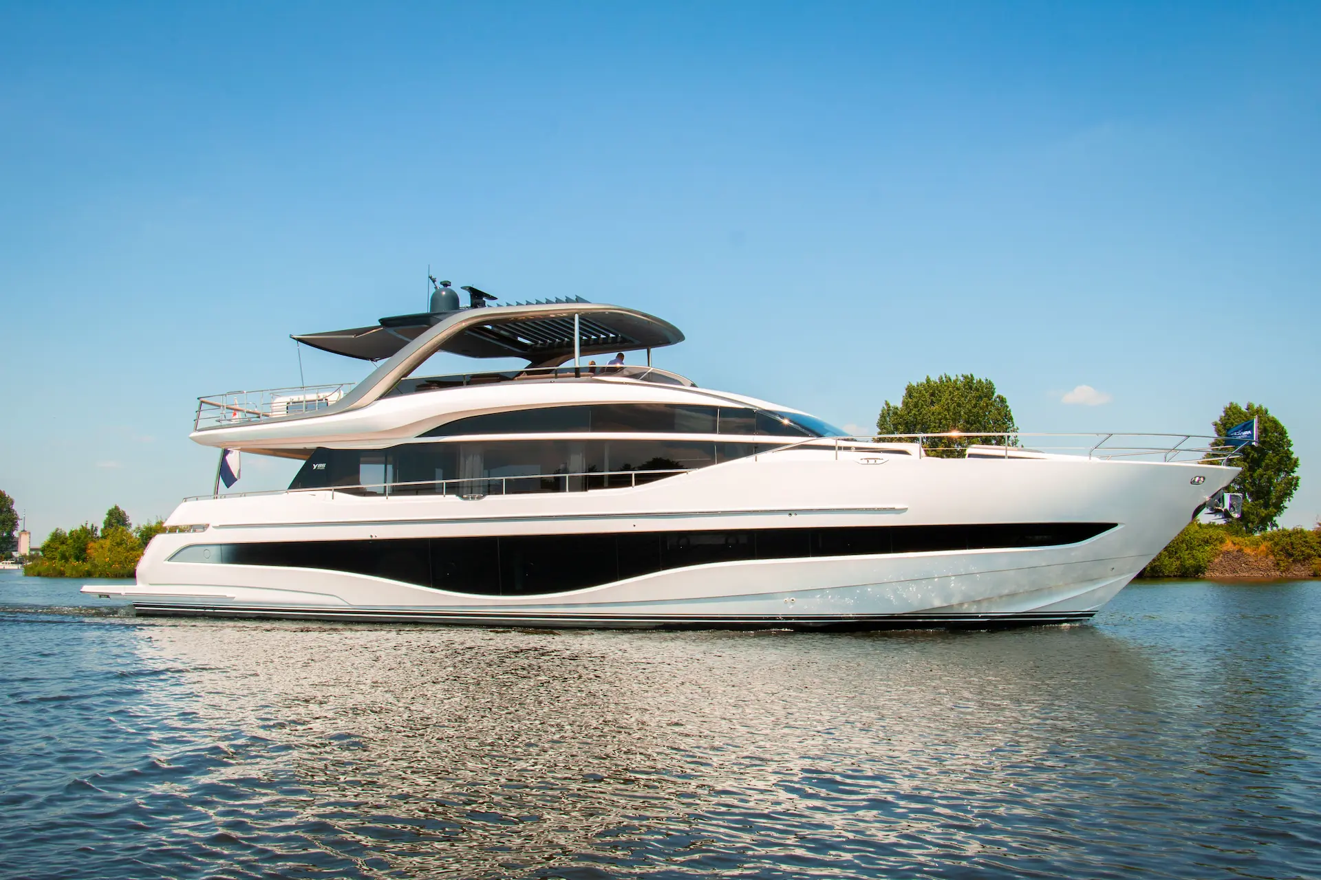 Luxe Princess Yacht vaart in een serene haven in Nederland onder een heldere blauwe lucht.