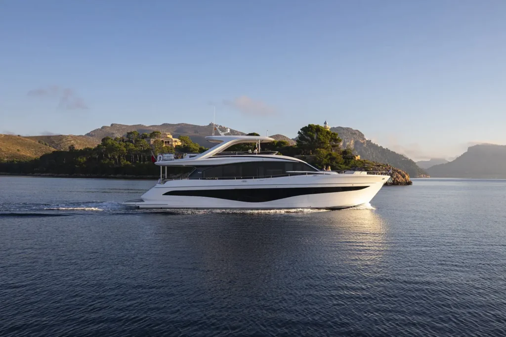 Een luxueuze Princess Yachts X Class serie vaart op een rustige zee met een bergachtig landschap in de achtergrond.