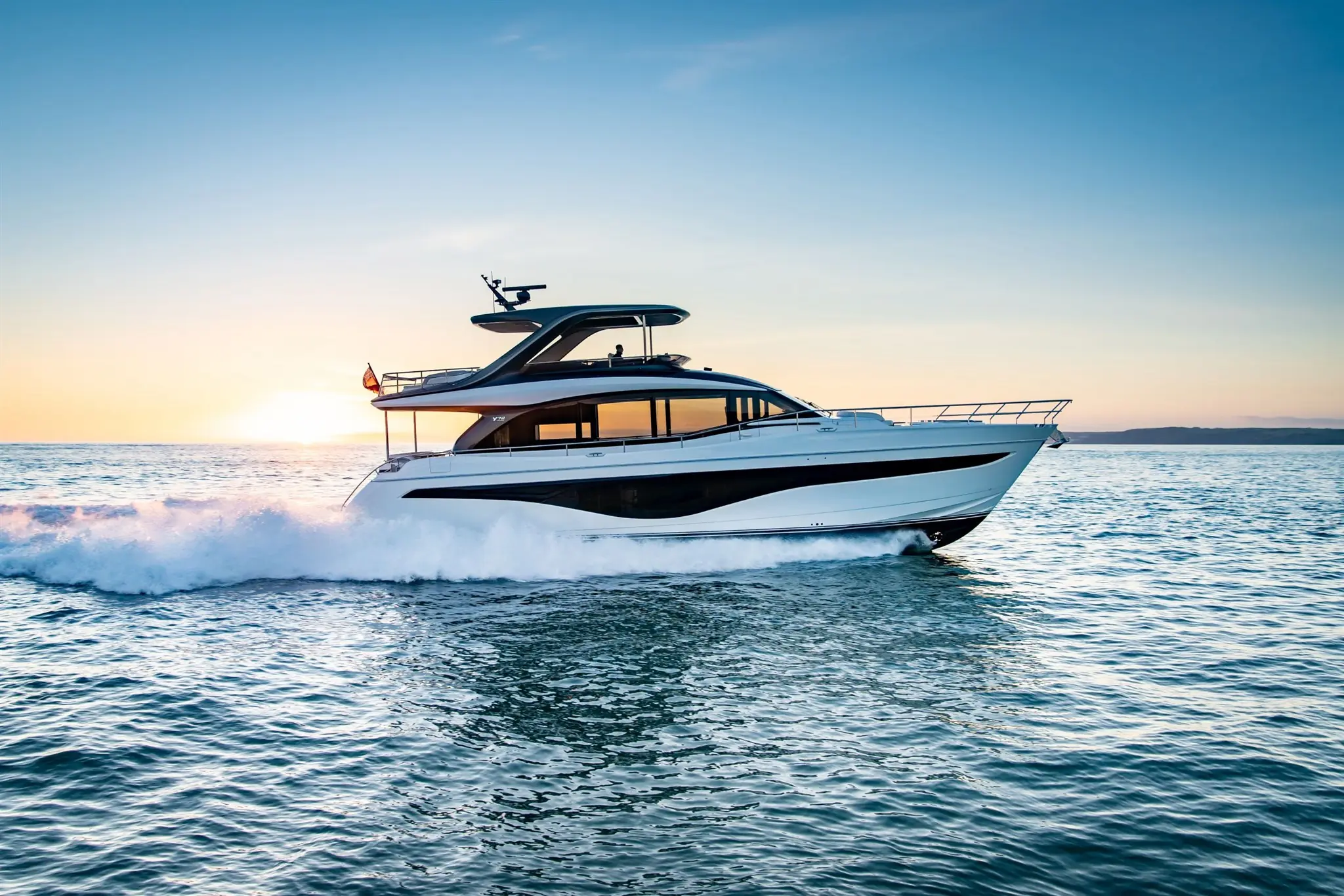 Een Princess Yachts Y-klasse jacht vaart over de oceaan bij zonsondergang.